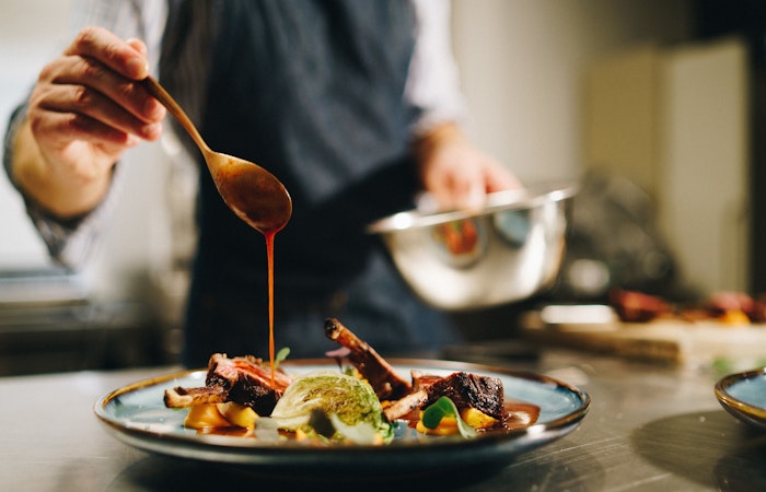 Chef pouring special sauce pork ribs kitchen